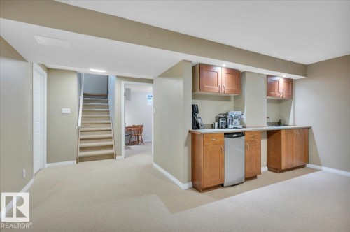 Recreation room featuring a wet bar area with cabinets, a sink, and a fridge - 705 Riddell Street, Edmonton, AB - Indoor