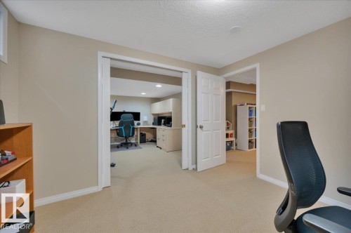 This versatile room features carpeted flooring and neutral-toned walls, offering a blank canvas for personalization - 705 Riddell Street, Edmonton, AB - Indoor Photo Showing Other Room