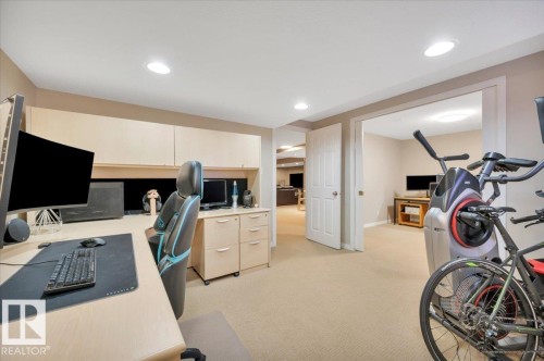 The property offers a versatile space with recessed lighting and neutral-toned carpeting, featuring a built-in desk area with overhead cabinetry and a filing cabinet - 705 Riddell Street, Edmonton, AB - Indoor