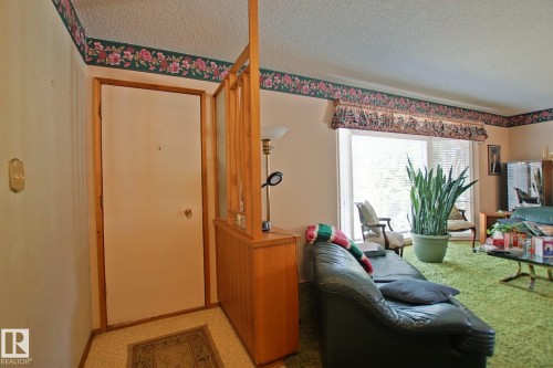 Entryway featuring a wood-panel accent wall and textured flooring - 3539 104 Street, Edmonton, AB - Indoor