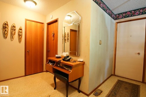 Entryway featuring multiple light wood-finish doors, a wall-mounted light fixture, and textured ceiling - 3539 104 Street, Edmonton, AB - Indoor Photo Showing Other Room