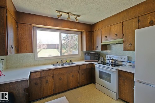 Kitchen featuring wood-finish cabinetry, white countertops, and a double basin sink - 3539 104 Street, Edmonton, AB - Indoor Photo Showing Kitchen With Double Sink