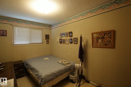 Bedroom featuring a window with horizontal blinds, textured ceiling, and neutral wall tones - 3539 104 Street, Edmonton, AB - Indoor Photo Showing Bedroom