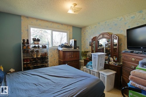 Room featuring a window with exterior views, textured ceiling, and a ceiling-mounted light fixture - 3539 104 Street, Edmonton, AB - Indoor Photo Showing Bedroom