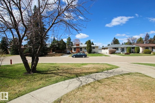 Residential street scene featuring single-story homes with front lawns and concrete sidewalks - 3539 104 Street, Edmonton, AB - Outdoor