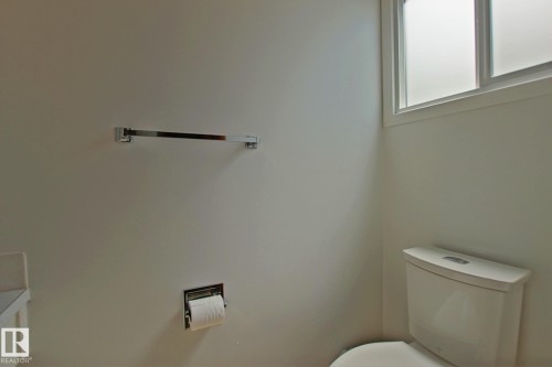 Bathroom featuring a white toilet, chrome towel bar, and a frosted window - 3539 104 Street, Edmonton, AB - Indoor Photo Showing Bathroom