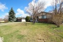 Two-tone exterior featuring brick and light-colored siding, a mature evergreen tree, and a green lawn - 3539 104 Street, Edmonton, AB  - Outdoor 