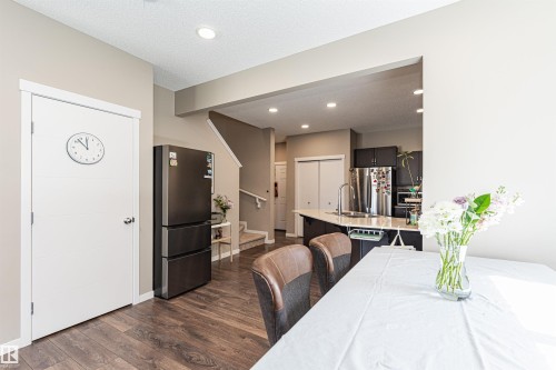Open-concept kitchen and dining area featuring dark wood-finish flooring - 4452 Annett Common, Edmonton, AB 