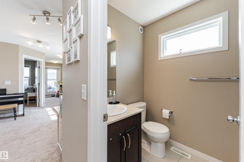Powder room featuring a single vanity with a white basin and dark wood-finish cabinetry, a rectangular window, and a white toilet - 4452 Annett Common, Edmonton, AB 