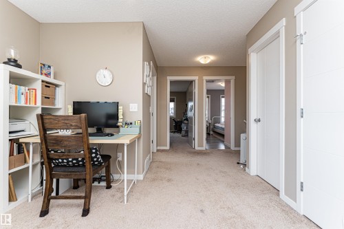 Carpeted hallway featuring light neutral wall paint, white trim, and white paneled interior doors - 4452 Annett Common, Edmonton, AB 