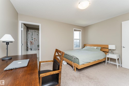 Bedroom featuring neutral wall tones, carpeted flooring, a flush-mount ceiling light fixture, and a window with a white frame - 4452 Annett Common, Edmonton, AB 
