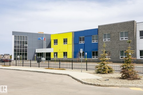 Modern institutional building featuring a multi-toned exterior with gray panels, vibrant yellow siding, and blue accents - 4452 Annett Common, Edmonton, AB 