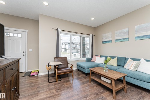 Open-concept living area with wood-finish flooring, neutral wall tones, and recessed lighting - 4452 Annett Common, Edmonton, AB 