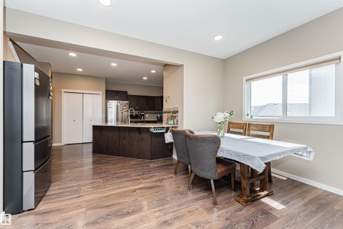 Dining area featuring wood-finish flooring, a large window, recessed lighting, and an open concept layout into the kitchen - 4452 Annett Common, Edmonton, AB 