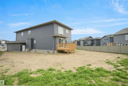 Rear exterior of a two-story residence featuring grey siding, multiple windows, and a ground-level deck with wooden railing - 22139 81 Avenue, Edmonton, AB - Outdoor With Exterior