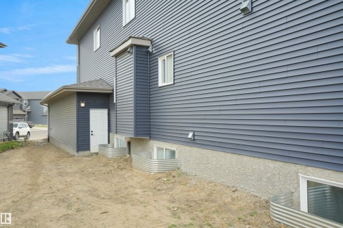 Exterior featuring dark blue horizontal siding, white trim windows, and a foundation with a textured finish - 22139 81 Avenue, Edmonton, AB - Outdoor With Exterior