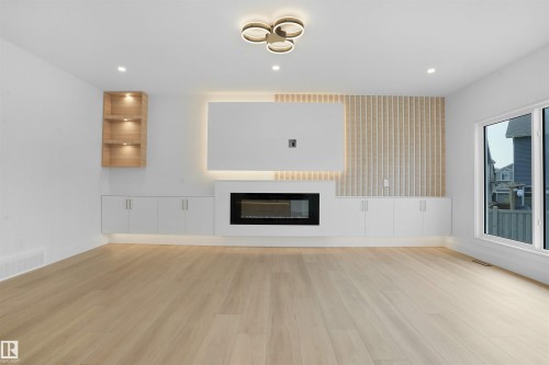 Living area featuring light wood-finish flooring, a built-in electric fireplace, recessed ceiling lighting, and a contemporary ceiling fixture - 22139 81 Avenue, Edmonton, AB - Indoor With Fireplace