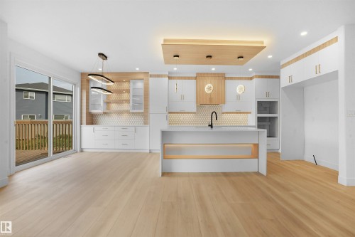 Modern kitchen featuring white cabinetry, a central island with a waterfall countertop, honeycomb tile backsplash, and light wood-finish flooring - 22139 81 Avenue, Edmonton, AB - Indoor
