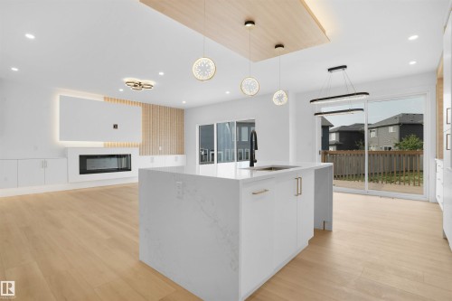 Contemporary open-concept living area featuring light wood-finish flooring - 22139 81 Avenue, Edmonton, AB - Indoor Photo Showing Kitchen With Fireplace