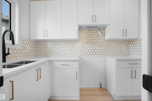 Bright kitchen featuring white cabinetry with gold-toned hardware, white countertops, a hexagon tile backsplash, and a black gooseneck faucet - 22139 81 Avenue, Edmonton, AB - Indoor Photo Showing Kitchen With Double Sink With Upgraded Kitchen
