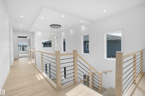 Upper-level hallway featuring light wood-finish flooring, recessed ceiling lighting, and a contemporary chandelier - 22139 81 Avenue, Edmonton, AB - Indoor