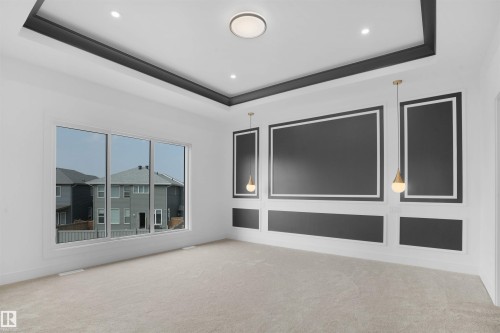Spacious room featuring a tray ceiling with recessed lighting, decorative wall paneling, a large multi-pane window, flush-mount ceiling light, and carpet flooring - 22139 81 Avenue, Edmonton, AB - Indoor Photo Showing Other Room