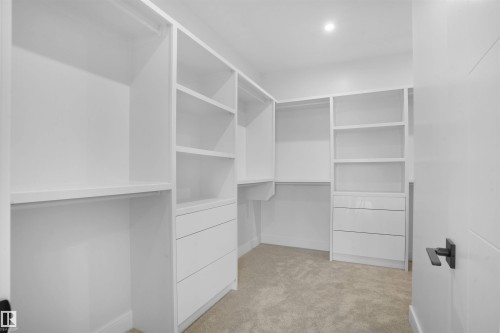 Walk-in closet featuring white built-in shelving, integrated drawers, hanging rods, recessed lighting, and carpet flooring - 22139 81 Avenue, Edmonton, AB - Indoor With Storage