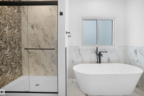 Freestanding soaking tub with matte black floor-mounted faucet, complemented by a walk-in shower featuring patterned tile and marble-look shower walls - 22139 81 Avenue, Edmonton, AB - Indoor Photo Showing Bathroom