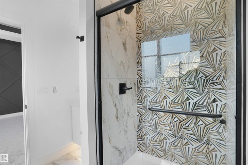 Modern shower enclosure featuring a striking geometric tile design, white marble-look accent wall, and matte black fixtures - 22139 81 Avenue, Edmonton, AB - Indoor