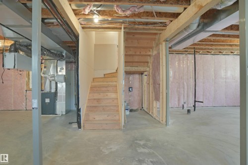 Unfinished basement featuring exposed wood framing, concrete flooring, and an unfinished wooden staircase - 22139 81 Avenue, Edmonton, AB - Indoor Photo Showing Basement
