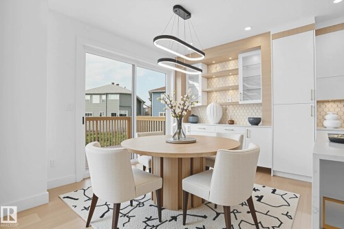 Dining area featuring light wood-finish flooring, a contemporary linear chandelier, and sliding glass doors leading to an outdoor deck - 22139 81 Avenue, Edmonton, AB - Indoor Photo Showing Dining Room