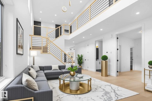 Two-story living area featuring a prominent staircase with wood railings and horizontal metal spindles, recessed ceiling lighting, light wood-finish flooring, and white painted walls - 22139 81 Avenue, Edmonton, AB - Indoor Photo Showing Living Room