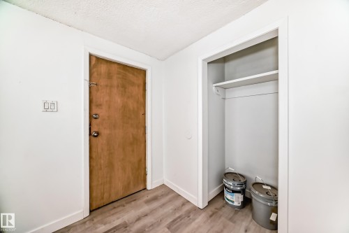 Entryway with wood-finish door, light wood-finish flooring, and a built-in closet with shelving and hanging rod - 12825 102 Street, Edmonton, AB - Indoor Photo Showing Other Room