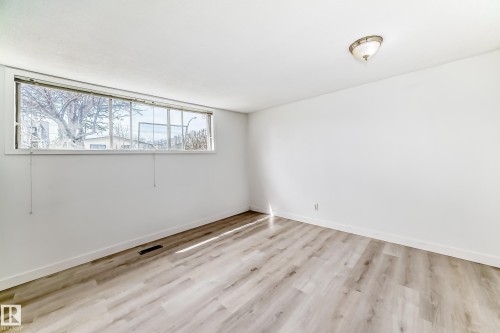 Bright room with wood-finish flooring, white walls, and a large horizontal window - 12825 102 Street, Edmonton, AB - Indoor Photo Showing Other Room