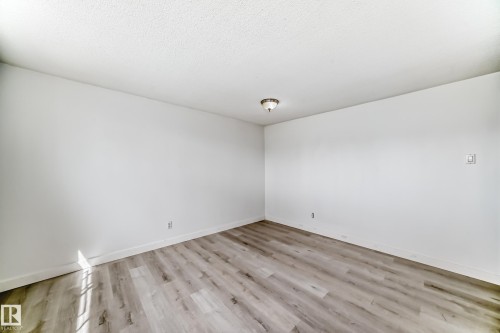 Room featuring wood-finish flooring, white walls, white baseboards, and a ceiling-mounted light fixture - 12825 102 Street, Edmonton, AB - Indoor Photo Showing Other Room
