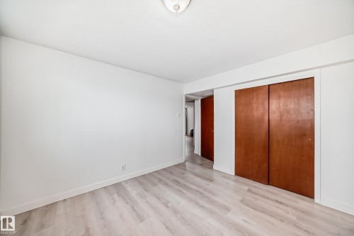 Light wood-finish flooring with white baseboards throughout - 12825 102 Street, Edmonton, AB - Indoor Photo Showing Other Room