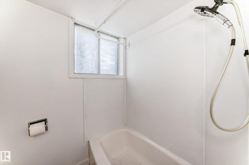 White-paneled shower/tub combination with a wall-mounted shower head and a small window - 12825 102 Street, Edmonton, AB - Indoor Photo Showing Bathroom