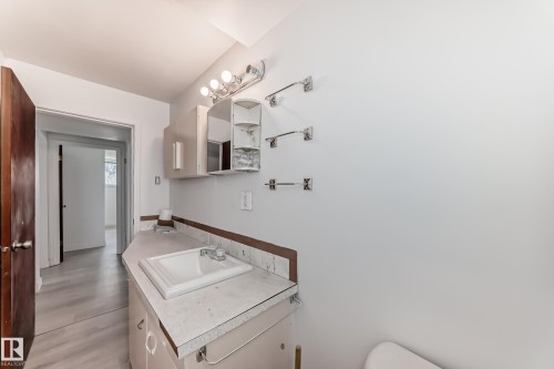 Bathroom vanity with integrated sink, overhead lighting, wall-mounted medicine cabinet, and three towel bars - 12825 102 Street, Edmonton, AB - Indoor Photo Showing Laundry Room