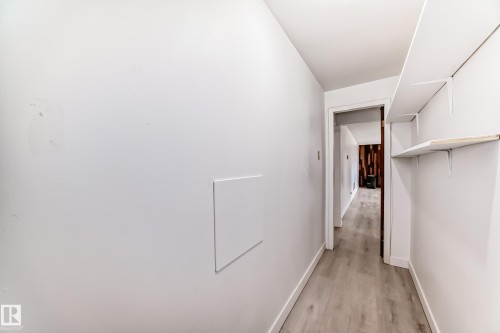 Hallway featuring light-toned wood-finish flooring, white walls, and built-in shelving - 12825 102 Street, Edmonton, AB - Indoor Photo Showing Other Room