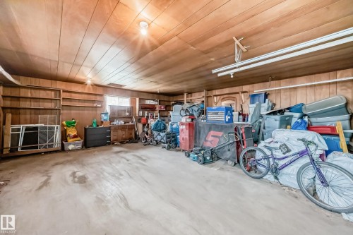 Spacious garage featuring wood-paneled walls and ceiling, concrete flooring, and built-in shelving - 12825 102 Street, Edmonton, AB - Indoor Photo Showing Garage