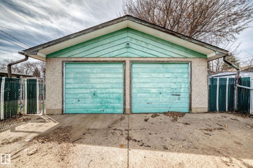 Detached two-car garage featuring a gabled roofline, concrete drive, stucco exterior finish, and horizontal panel garage doors - 12825 102 Street, Edmonton, AB - Outdoor