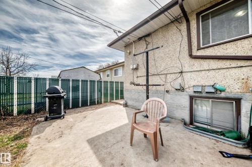 Exterior concrete patio with a full-height green privacy fence - 12825 102 Street, Edmonton, AB - Outdoor With Exterior