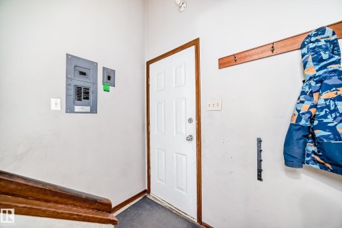 Utility area featuring an electrical panel, a white paneled door with wood-finish trim, and a wood-finish handrail - 12825 102 Street, Edmonton, AB - Indoor Photo Showing Other Room