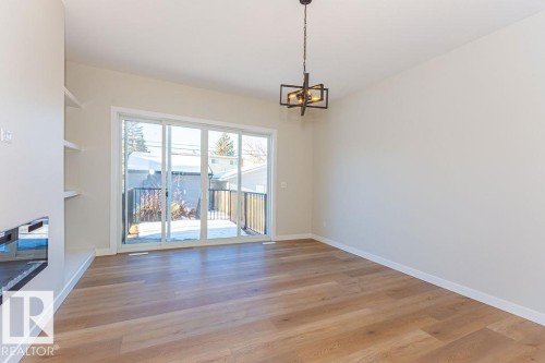 Spacious room featuring wood-finish flooring, a contemporary chandelier, a built-in fireplace, and integrated shelving - 9814 155 Street, Edmonton, AB - Indoor Photo Showing Other Room