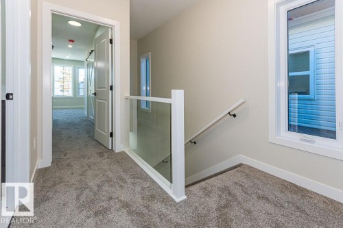 Carpeted hallway with a glass panel railing and white newel post - 9814 155 Street, Edmonton, AB - Indoor Photo Showing Other Room