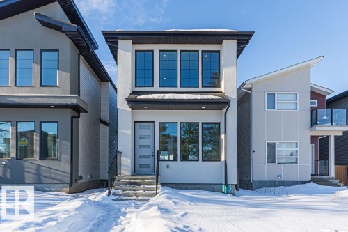 Modern exterior featuring a light-colored facade, multi-pane windows, black trim, and a contemporary front door with vertical panels - 9814 155 Street, Edmonton, AB - Outdoor With Facade