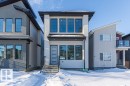 Modern exterior featuring a light-colored facade, multi-pane windows, black trim, and a contemporary front door with vertical panels - 9814 155 Street, Edmonton, AB  - Outdoor With Facade 