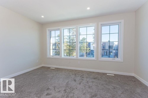 Bright room featuring three large windows with grid patterns, recessed lighting, neutral wall paint, white trim, and gray carpet - 9814 155 Street, Edmonton, AB - Indoor Photo Showing Other Room