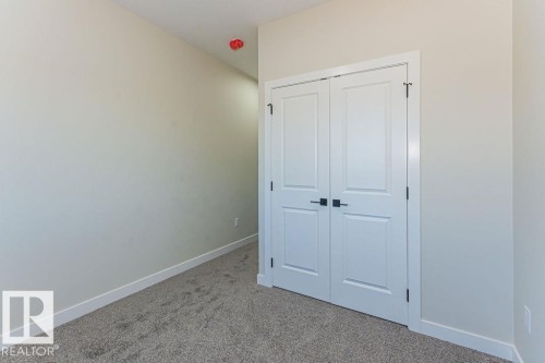 Double white panel doors featuring matte black hardware, light neutral walls, and gray carpet flooring - 9814 155 Street, Edmonton, AB - Indoor Photo Showing Other Room