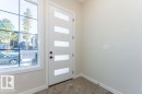 Entryway featuring a contemporary door with frosted glass panels and matte black hardware, a large grid-patterned window, light neutral wall paint, and textured carpeting - 9814 155 Street, Edmonton, AB  - Indoor Photo Showing Other Room 